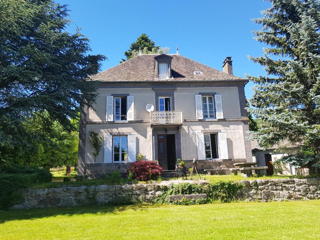 ein großes weißes Haus mit einer Veranda auf einem Rasen in der Unterkunft Domaine les Pradets in La Bourboule