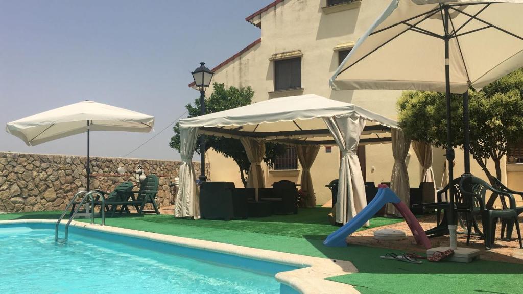 a swimming pool with two umbrellas and a swimming pool at Apartamentos de Astroturismo la Cañada in Torrejón el Rubio