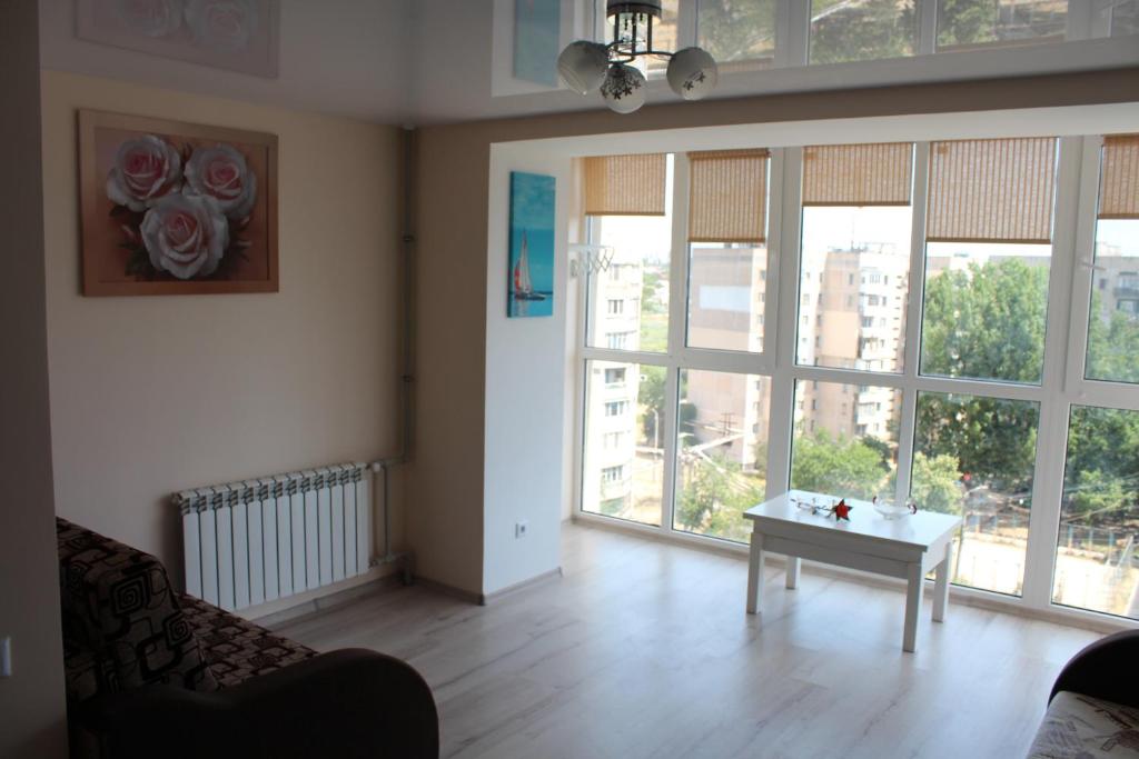 sala de estar con mesa y ventanas grandes en Morskoi dom, en Odessa