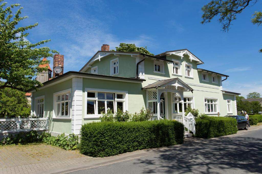 een groot groen en wit huis met een hek bij Haus Rosengarten in Middelhagen