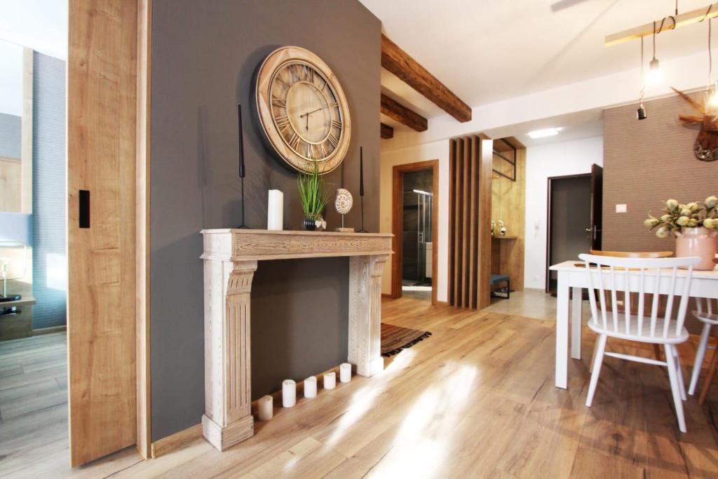 a living room with a fireplace and a clock on a wall at Zlatý Apartmán, Granit 106 in Vysoke Tatry - Tatranska Lomnica.