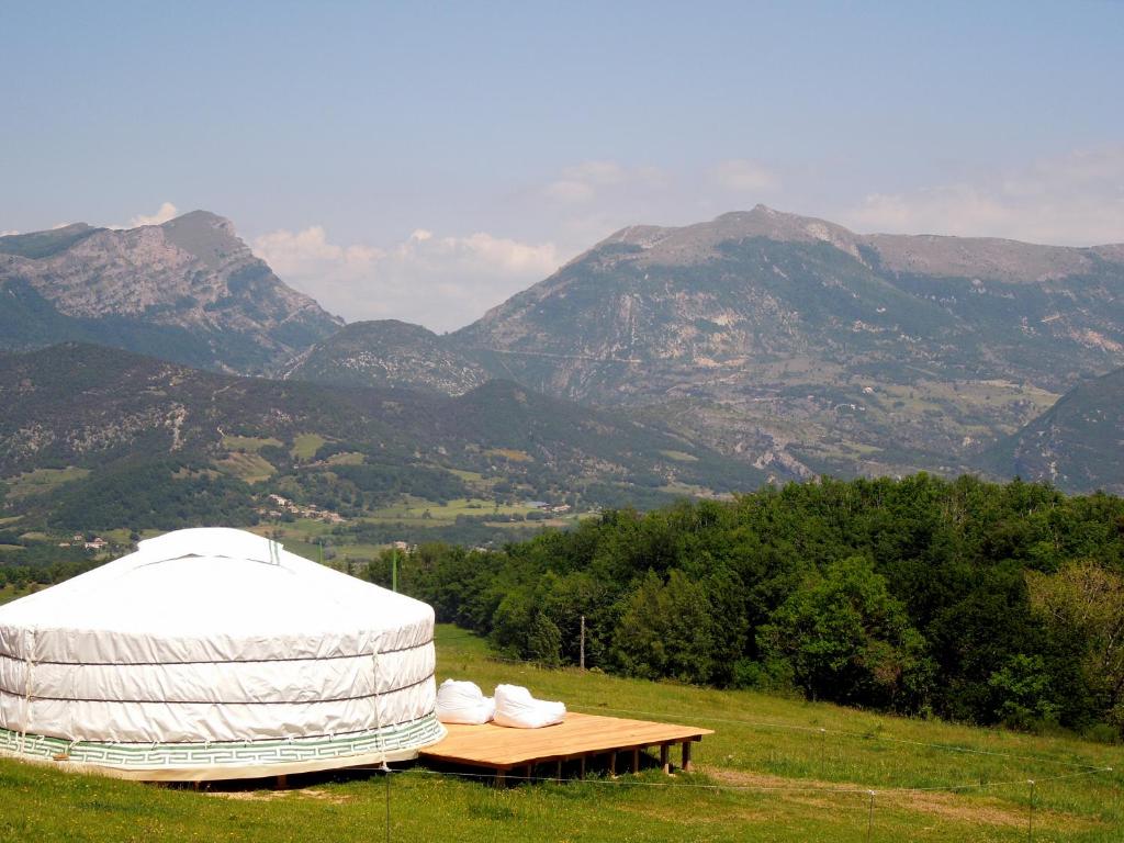 a yurt on a field with mountains in the background at Drome esprit nature in Le Poët-Célard