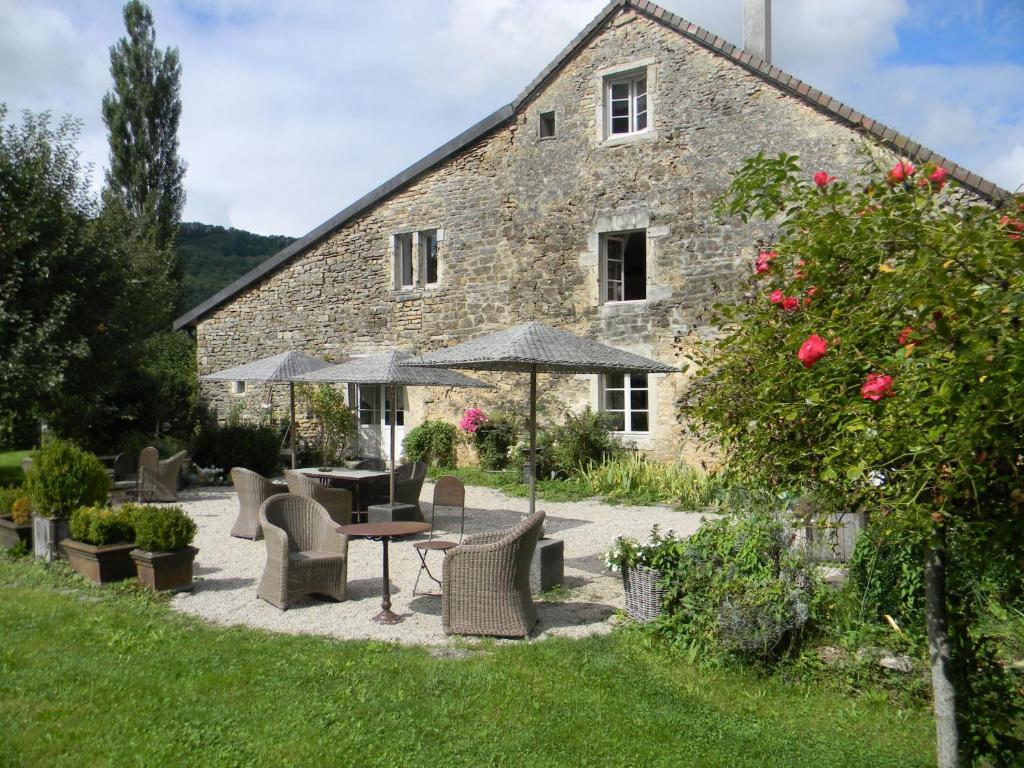 a stone building with a table and chairs and umbrellas at La Grange à Nicolas in Baume-les-Messieurs