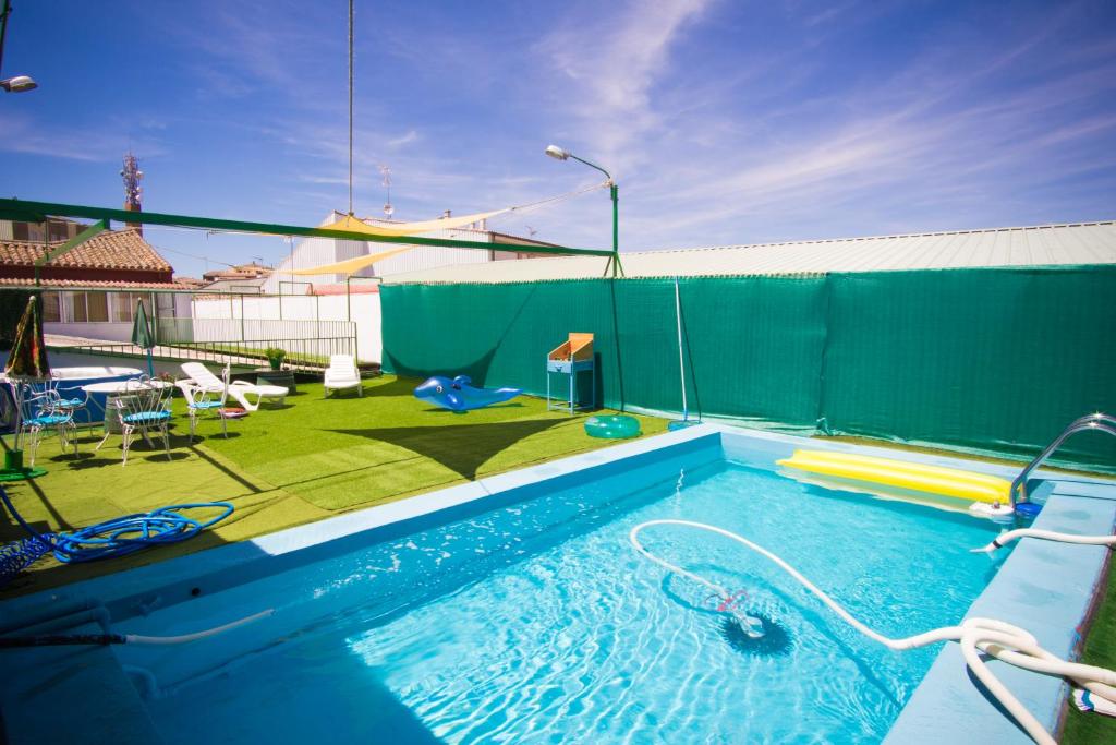 a swimming pool with a green privacy fence and a backyard at Casa Rural Arribes Vida I in Vitigudino