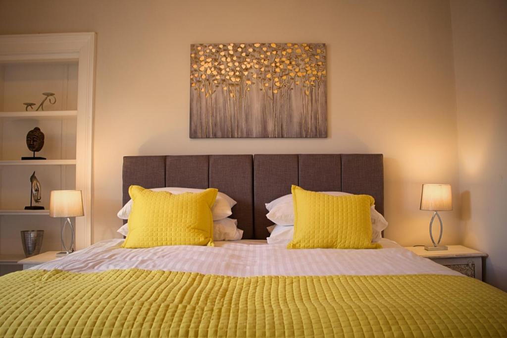 a bedroom with a large bed with yellow pillows at Wallace View Apartment in Stirling