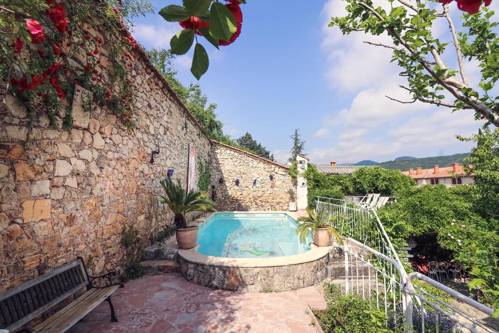 einen Whirlpool in einer Steinmauer mit einer Bank in der Unterkunft La Roseraie in Lodève