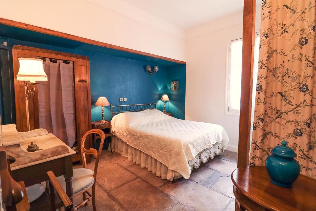 1 dormitorio con paredes azules y 1 cama con mesa en La Roseraie, en Lodève