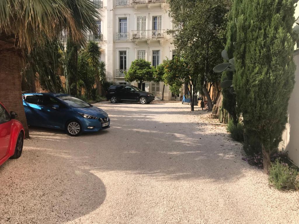 deux voitures garées dans une rue en face d'un bâtiment dans l'établissement Aux Iles d'Or, à Hyères