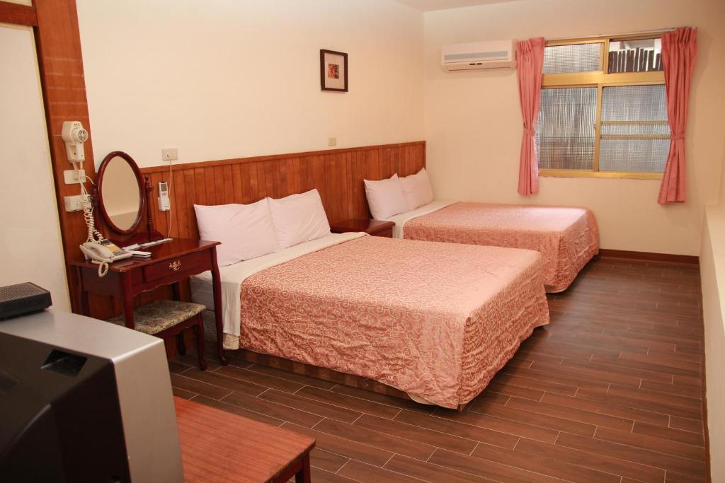 a hotel room with two beds and a television at Qingxiu Hotel in Baihe