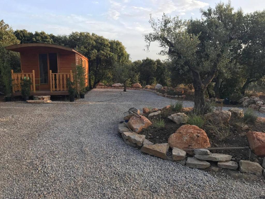 une cabane avec une allée en gravier avec un arbre et des rochers dans l'établissement roulotte, à Cournonterral