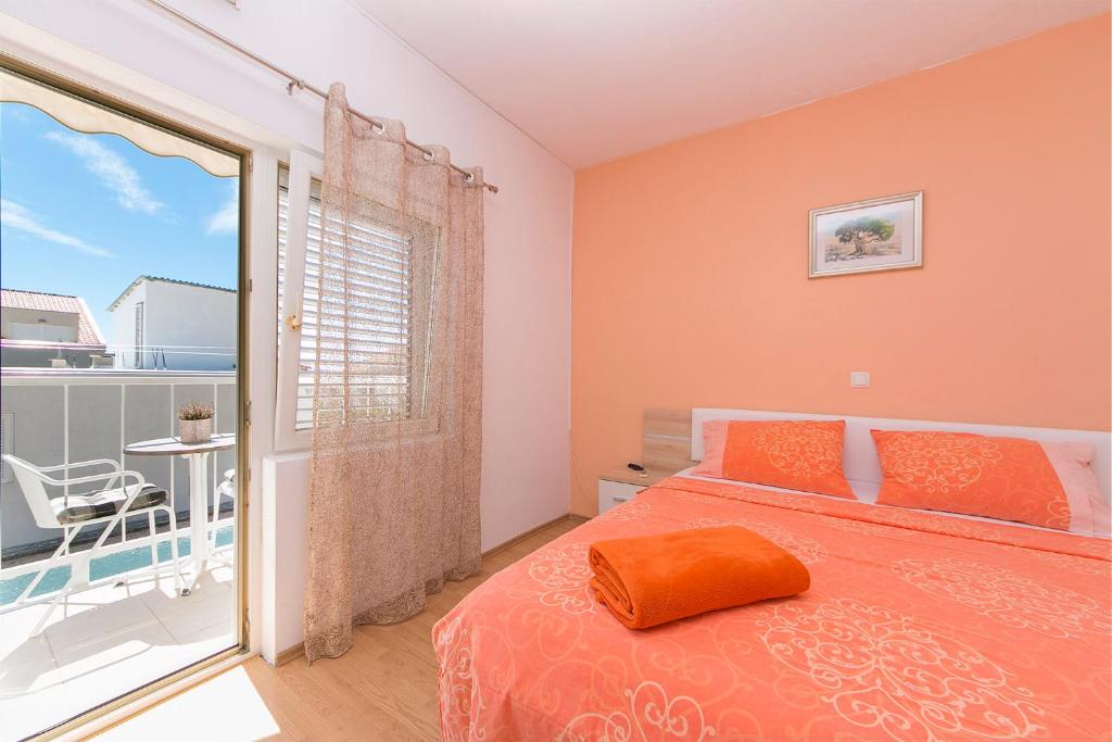 ein Schlafzimmer mit einem orangenen Bett und einem Balkon in der Unterkunft Apartment "San Marino" in Baška Voda