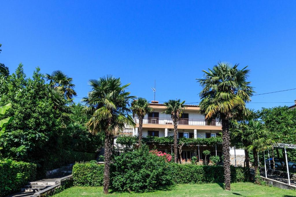 a building with palm trees in front of it at Rooms Sanja, Lovran - Opatija in Lovran