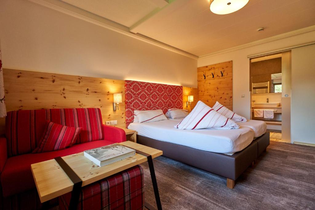オエッツにあるHotel Jägerhofのベッド2台とソファが備わるホテルルームです。