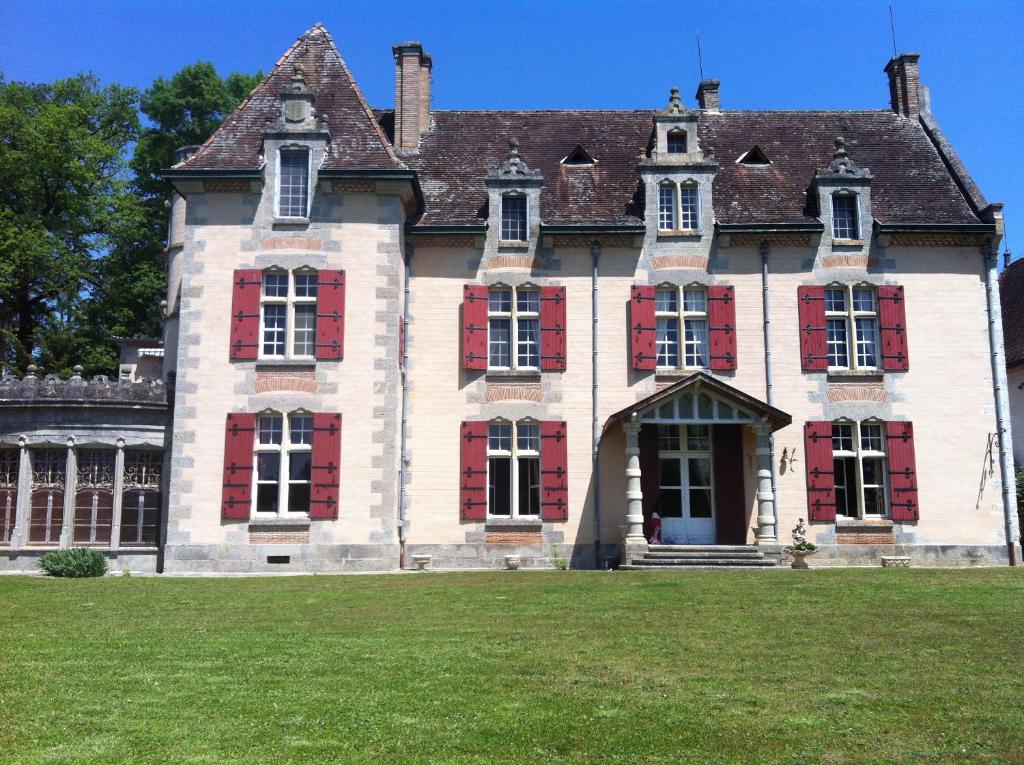 an old house with red shutters on a grass field at Château Logis de Roche in Clairac