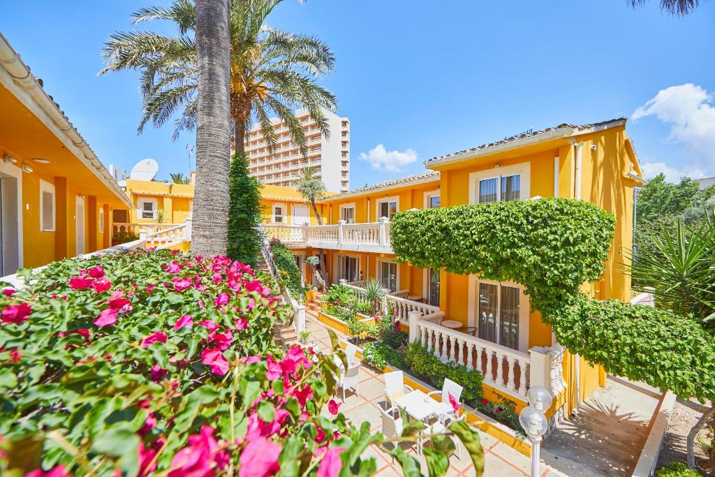 eine Reihe gelber Häuser mit rosa Blumen in der Unterkunft Hotel Cupidor in Paguera