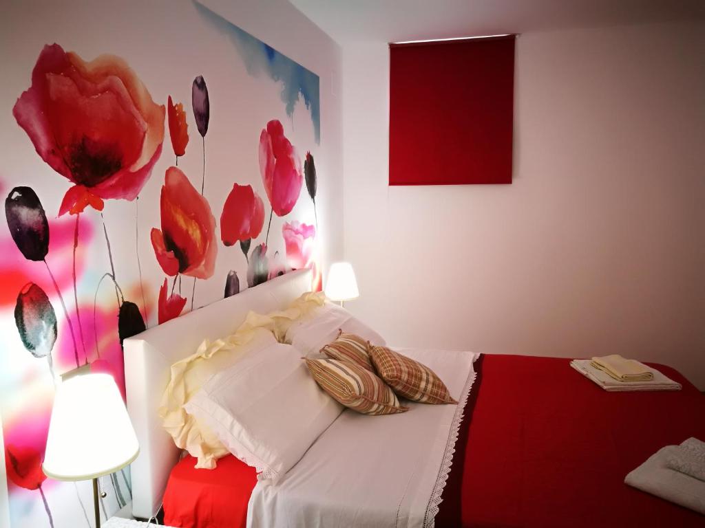 um quarto com uma cama vermelha e branca com flores vermelhas na parede em A casa di Vince Monteaperti em Montaperti