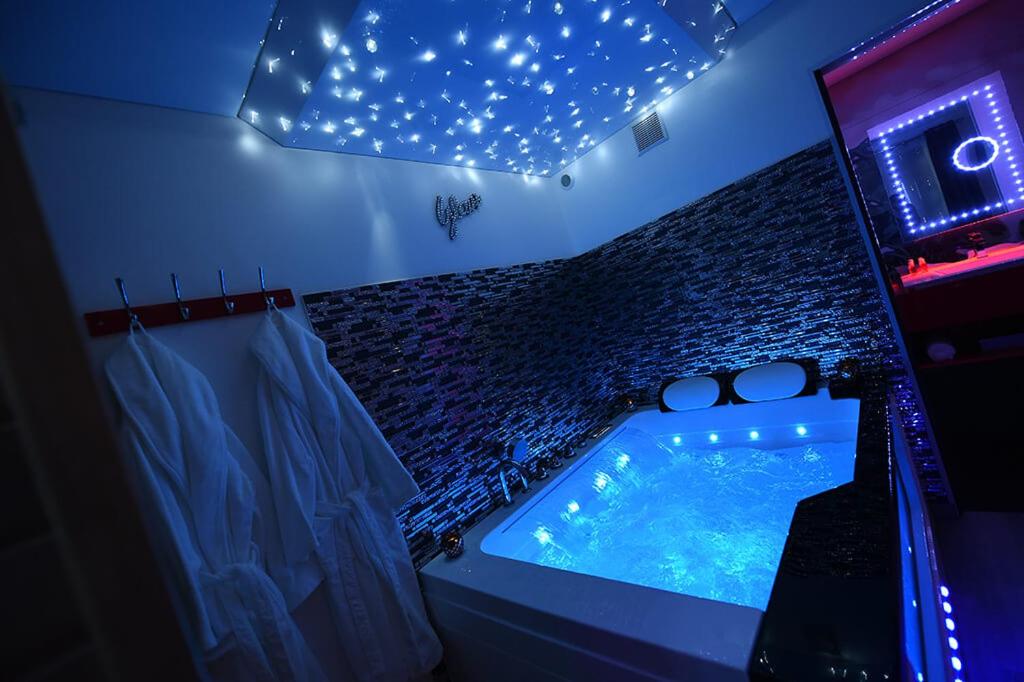 - une salle de bains avec baignoire dans une chambre éclairée dans l'établissement GlamappartSpa design luxe & Parking, à Dijon