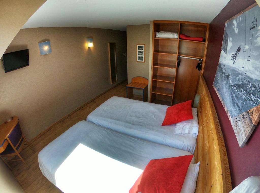 a small room with two beds and a shelf at Hôtel Les Arches in Saint-Lary-Soulan