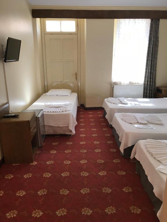 a room with three beds and a red carpet at Antik Ridvan Hotel in Çeşme