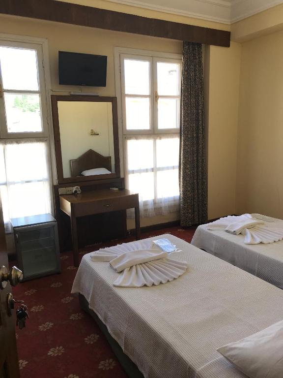 a hotel room with two beds and a mirror at Antik Ridvan Hotel in Çeşme