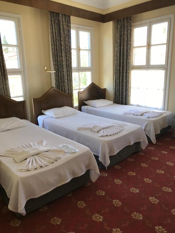 three beds in a hotel room with windows at Antik Ridvan Hotel in Çeşme