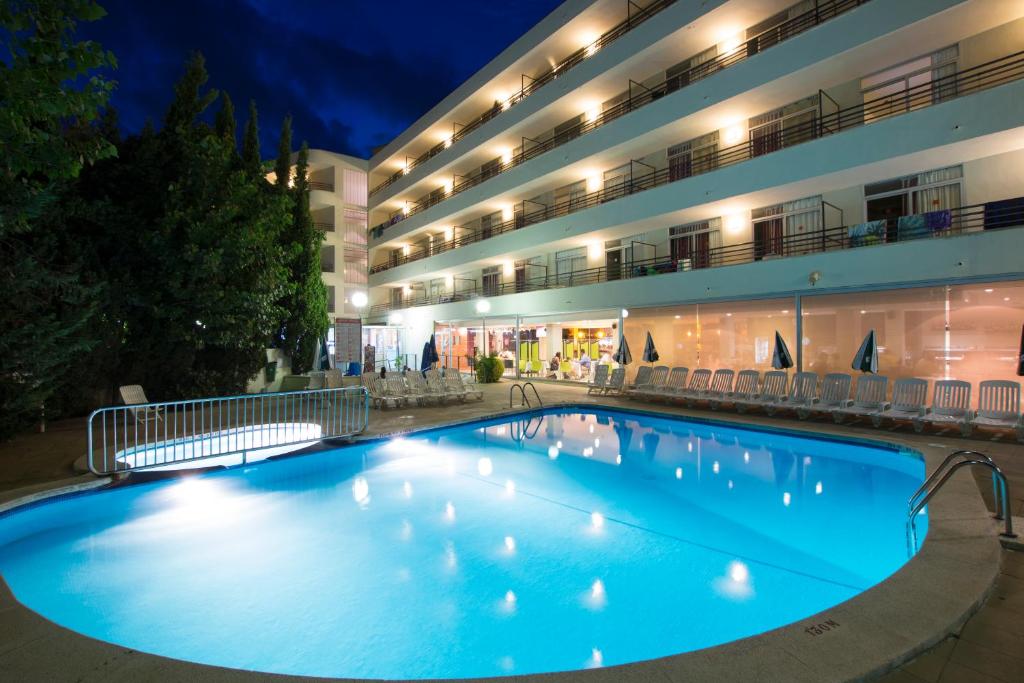 uma grande piscina em frente a um hotel à noite em Medplaya Aparthotel Esmeraldas em Tossa de Mar