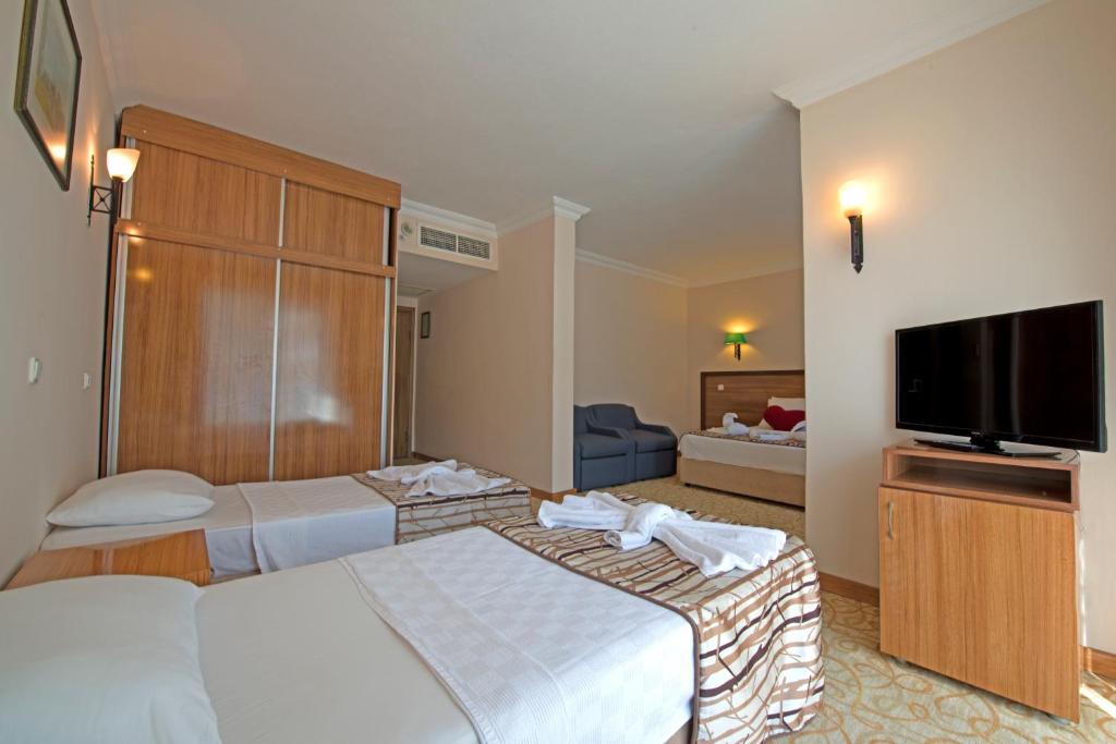 Una habitación de hotel con dos camas y un televisor de pantalla plana. en Green Nature Resort and Spa, en Marmaris