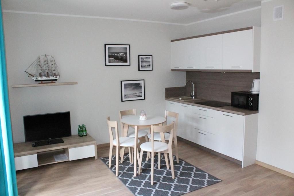 uma cozinha com mesa e cadeiras num quarto em Apartament Anna Park Rodzinna em Mielno