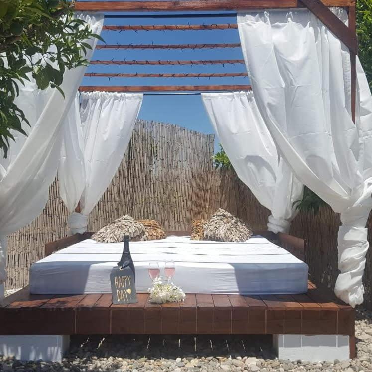 a bed with white curtains and two glasses on it at Finca Rayo del Sol in Alhaurín el Grande