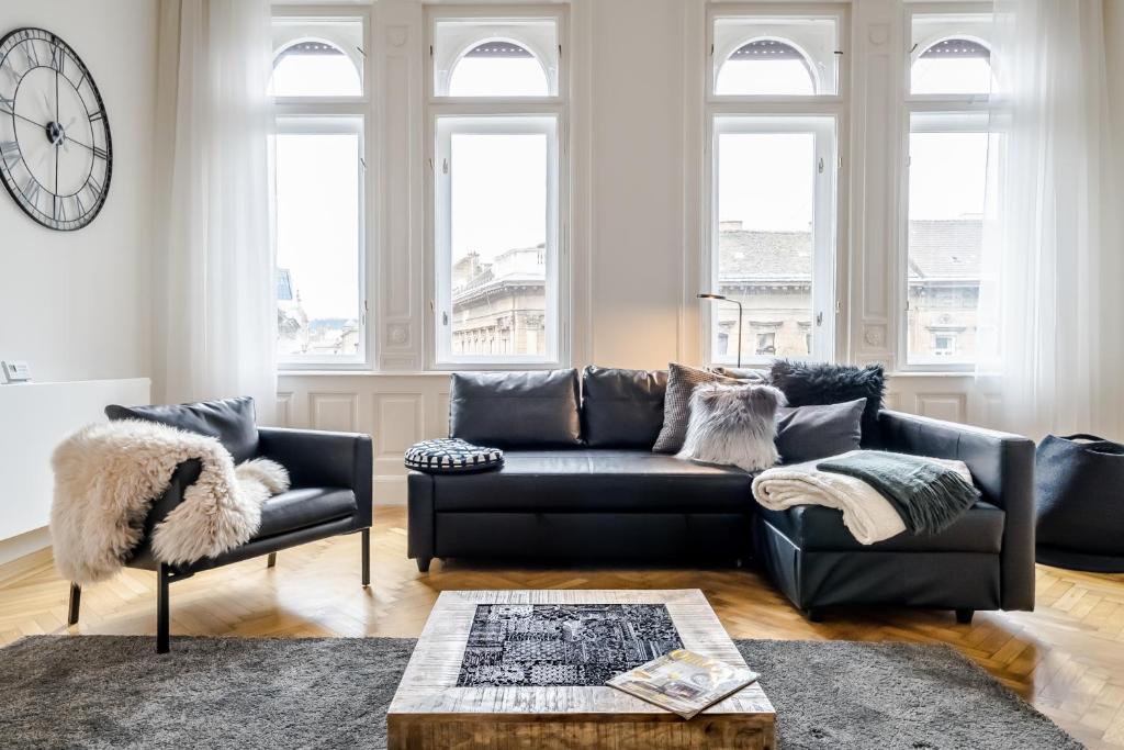 a living room with a black couch and a clock at BpR Luxe de Noir et Blanc Apartment in Budapest