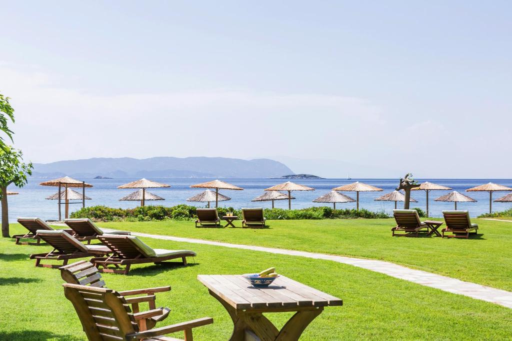 a group of chairs and tables and umbrellas on the grass at Milia Beach Apartments in Paralia Milia