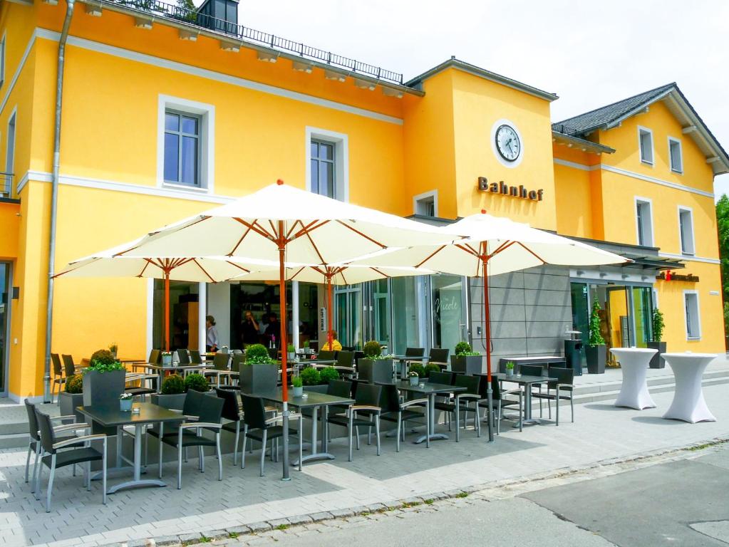 un restaurante con mesas y sombrillas frente a un edificio en Gleiseins, en Naila
