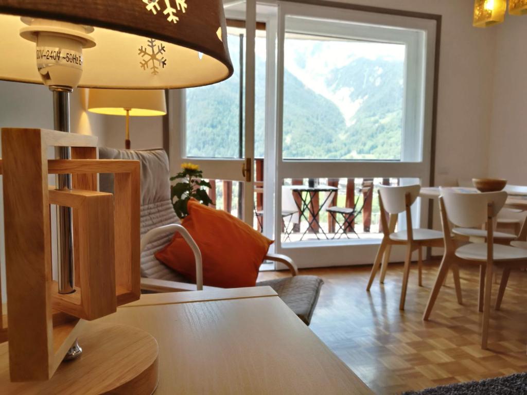 a living room with a table and chairs and a large window at L'Atelier du Temps - Hemmet in Courmayeur