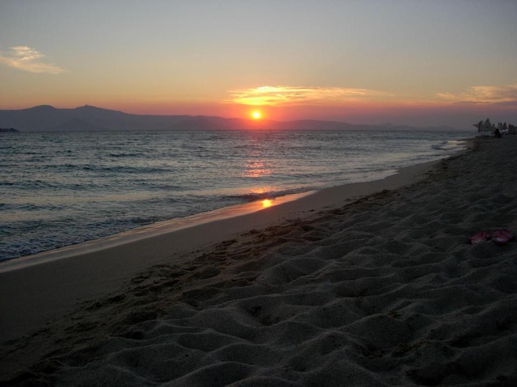 a sunset on a beach with the ocean at Blue Harmony Apartments in Plaka