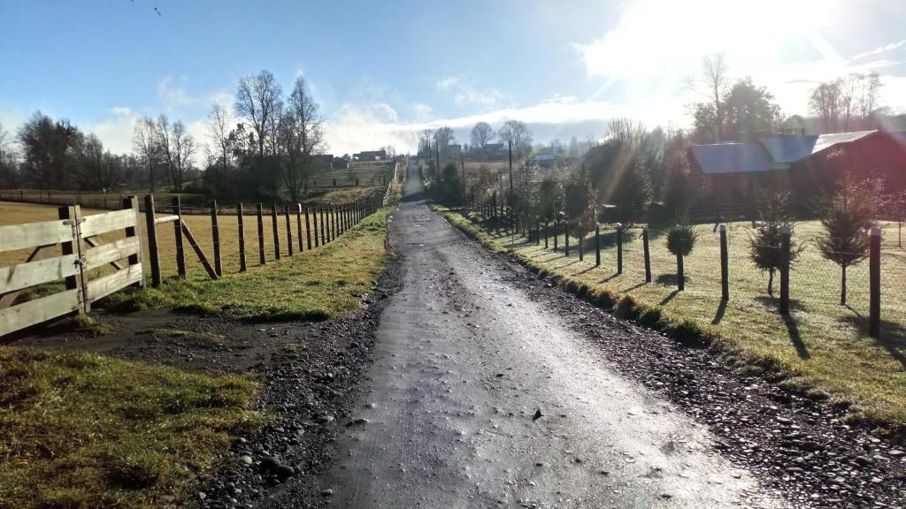 a dirt road in a field with a fence at Hostal Parcela 47 villarrica in Villarrica