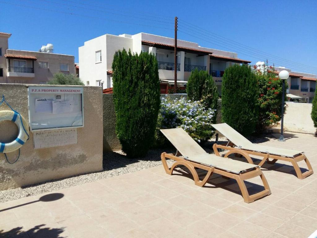 twee ligstoelen en een bord voor een gebouw bij By the sea in Paphos City