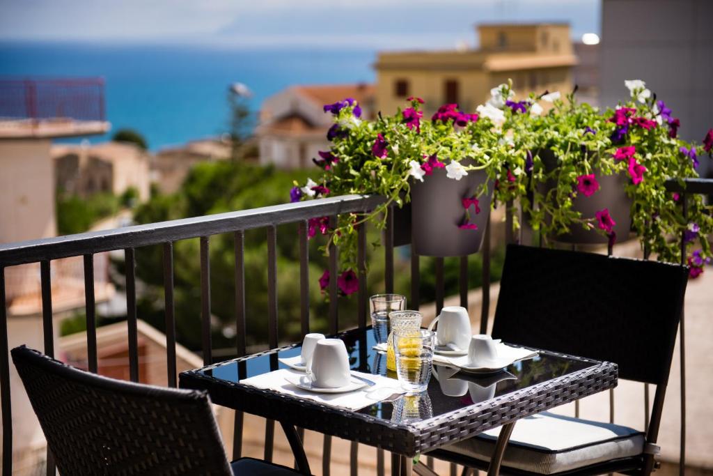 a table and chairs on a balcony with flowers at Mariú Rooms in Castellammare del Golfo