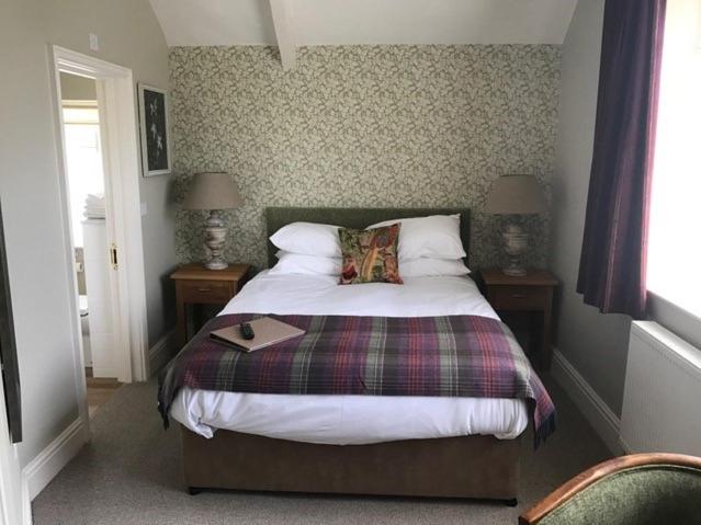 a bedroom with a bed and two tables with lamps at The George Inn - Lacock in Lacock
