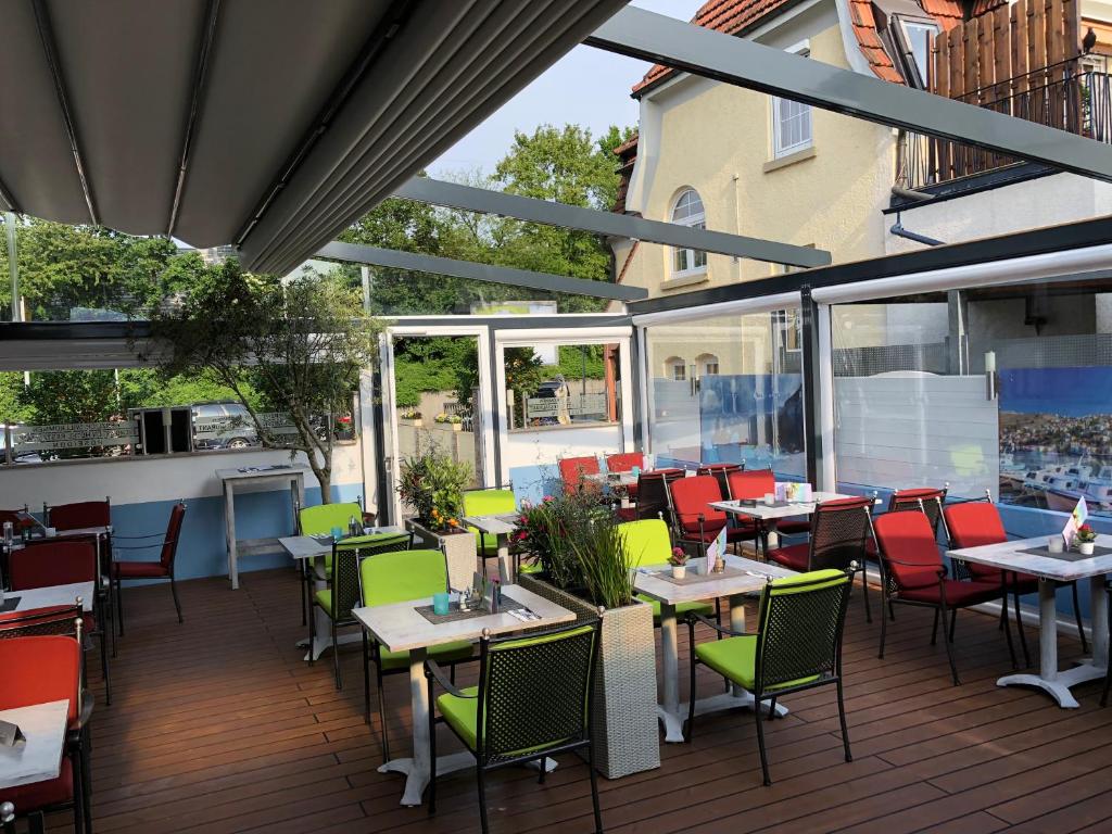 a restaurant with tables and chairs on a deck at Hotel Poseidon in Ludwigsburg