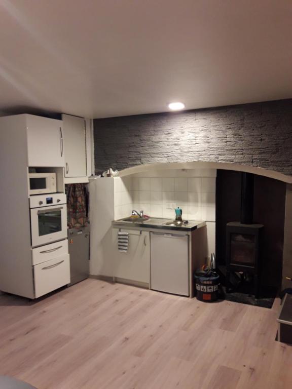 eine Küche mit weißen Geräten und einer Ziegelwand in der Unterkunft maison cosy proche de la station de ski du lioran 4 personnes in Thiézac
