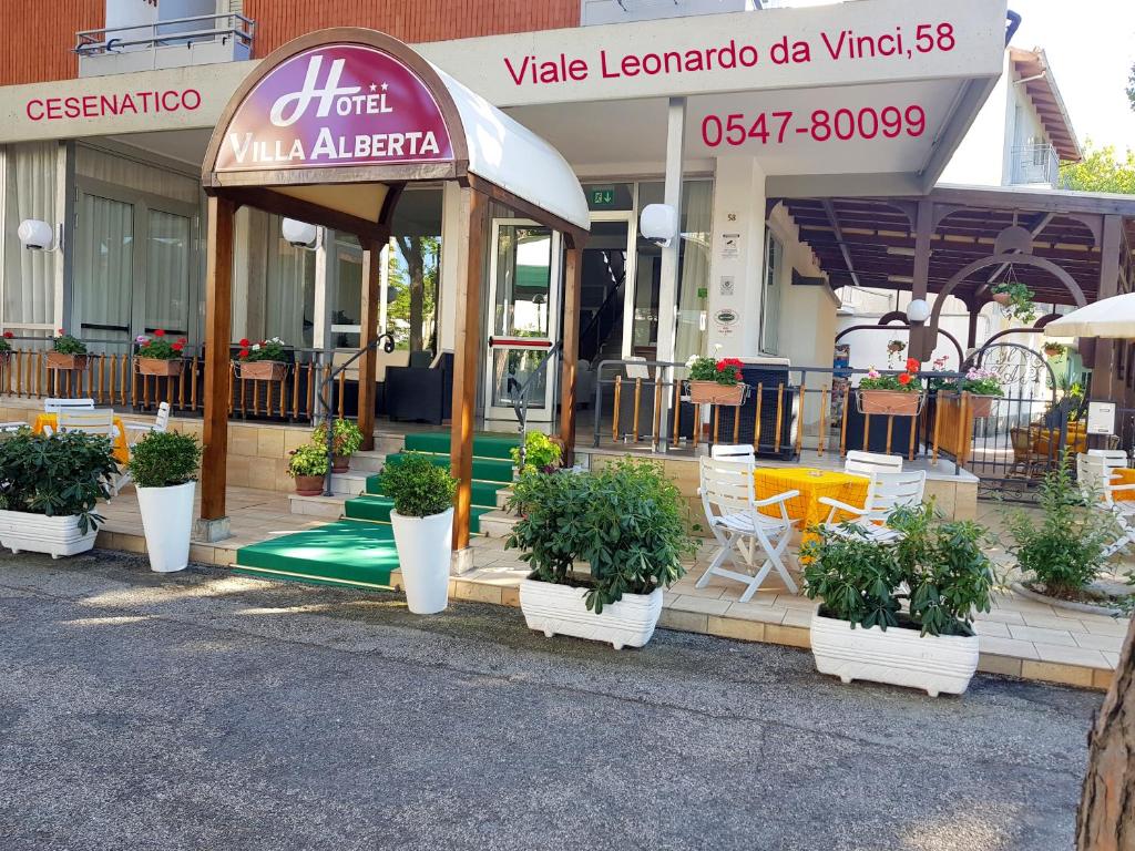 a restaurant with potted plants in front of a building at Hotel Villa Alberta B&B in Cesenatico