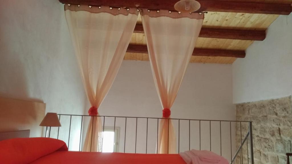a bedroom with white curtains and a red bed at Casa Maruzza in Donnalucata