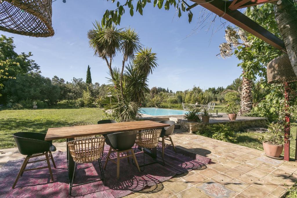 een patio met een tafel en stoelen en een zwembad bij Domaine Sesquier Mas d'exception Belle de Nuit in Mèze