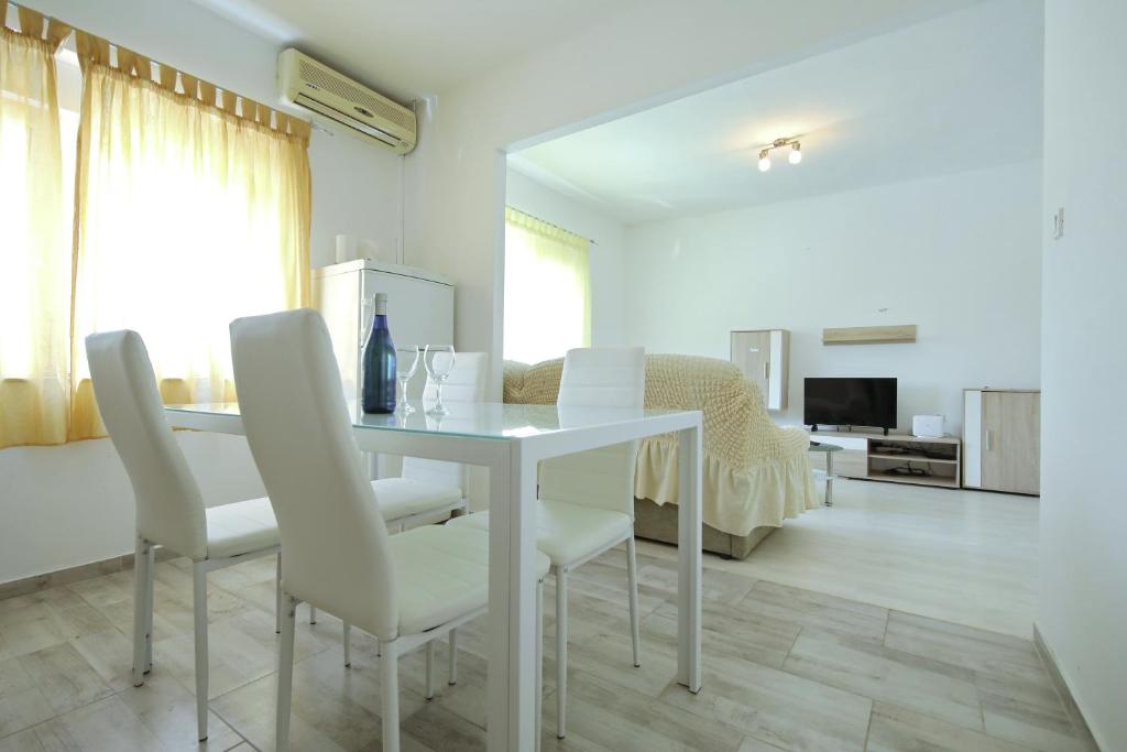 a white dining room with a white table and chairs at Apartment Mirela in Zadar