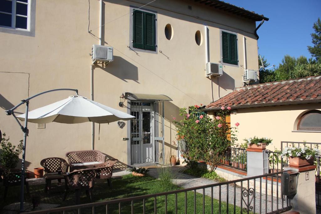 a patio with a table and an umbrella in front of a house at Relais Le Ortensie in Pisa