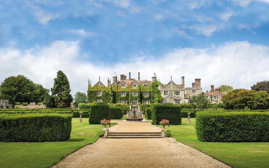 a house with a fountain in the middle of a garden at Eastwell Manor, Champneys Hotel & Spa in Ashford