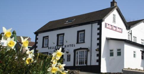 a white building with yellow flowers in front of it at Belle Vue Hotel in Llanwrtyd Wells
