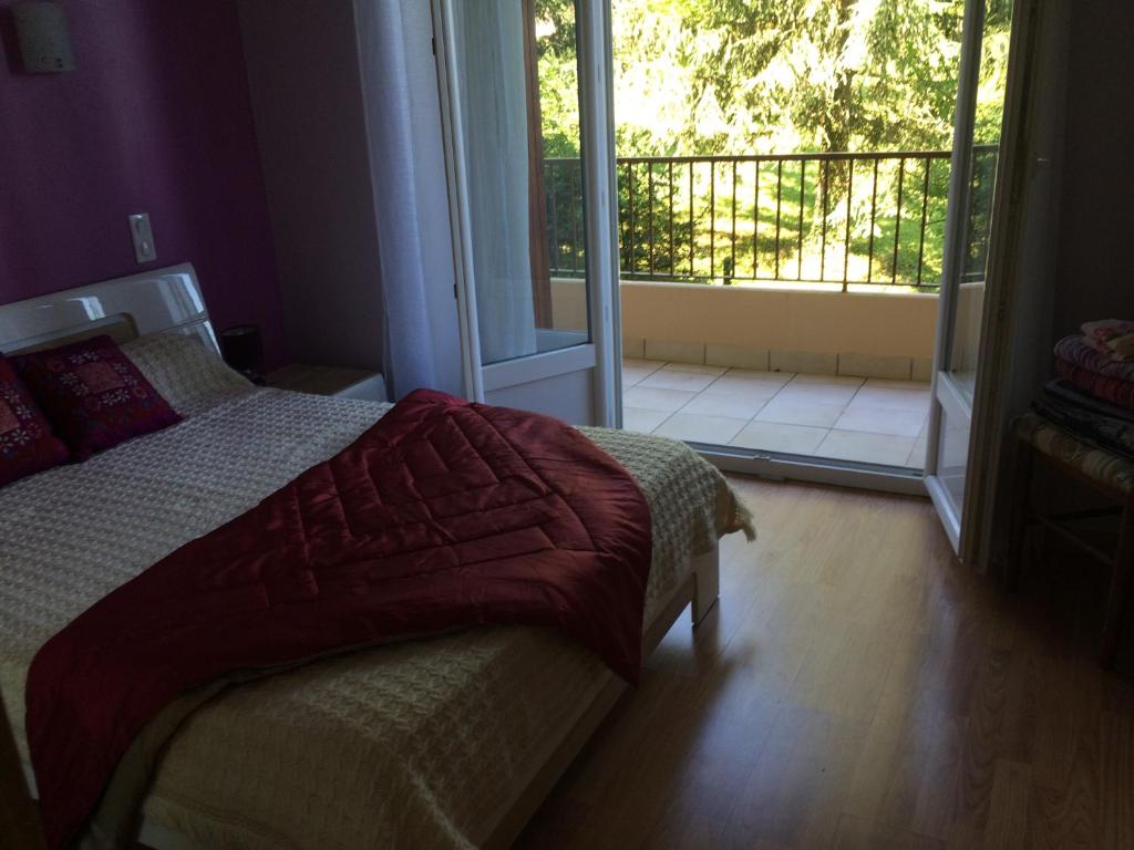 - une chambre avec un lit et une porte donnant sur un balcon dans l'établissement T2 gîte de Laurette avec garage et parking privés, à Rodez