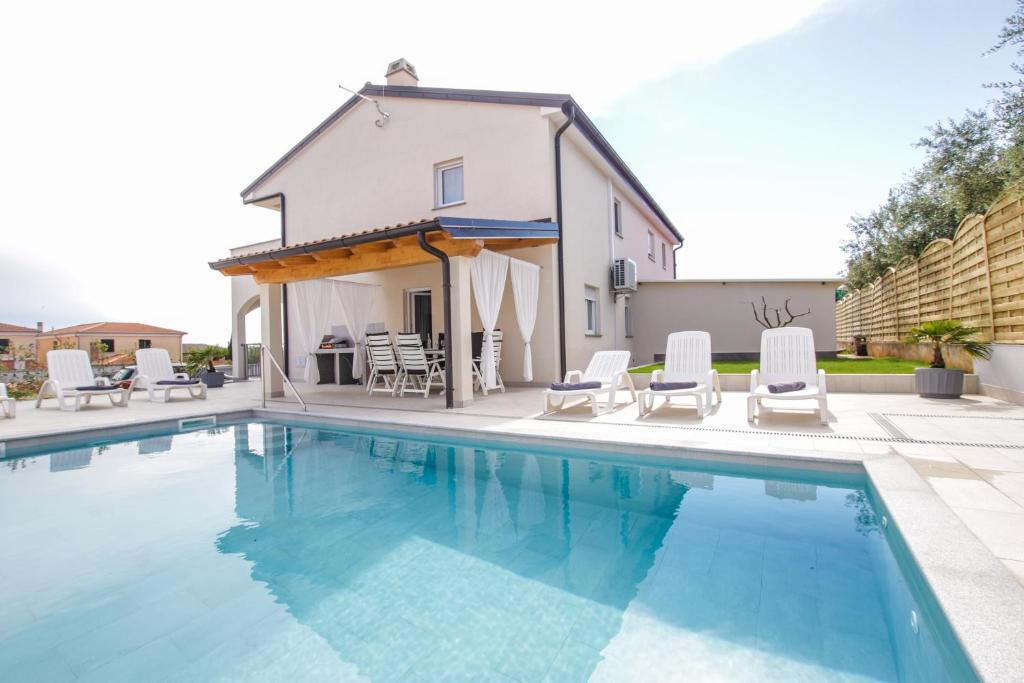 einen Pool mit Stühlen und ein Haus in der Unterkunft Villa Silver Novigrad with private pool in Novigrad Istria