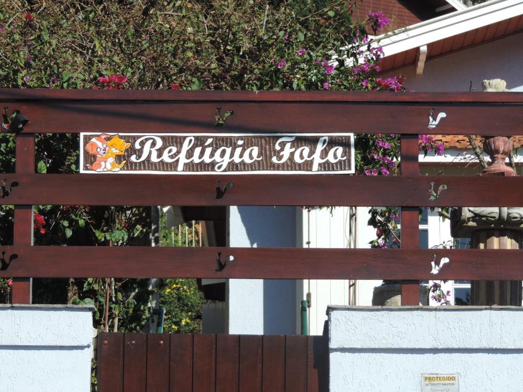 un cartello sul retro di una recinzione di legno di Refugio Fofo - casa de temporada a Campos do Jordão